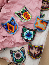 _<h2>Celebrating Huichol Craftsmanship</h2> <p>Each cat on each bottle is an individual handmade creation of a Huichol artist. It takes a full day to make three cat faces. Preserving traditional artisanal craftsmanship is a deliberate goal, both by sponsoring a craft agave spirit and by providing a livelihood to Huichol artisans.  The culture is noted for using peyote in religious ceremonies. Their elaborate yarn weaving and beadwork has shamanistic overtones, and the imagery is often based on dreams.</p>